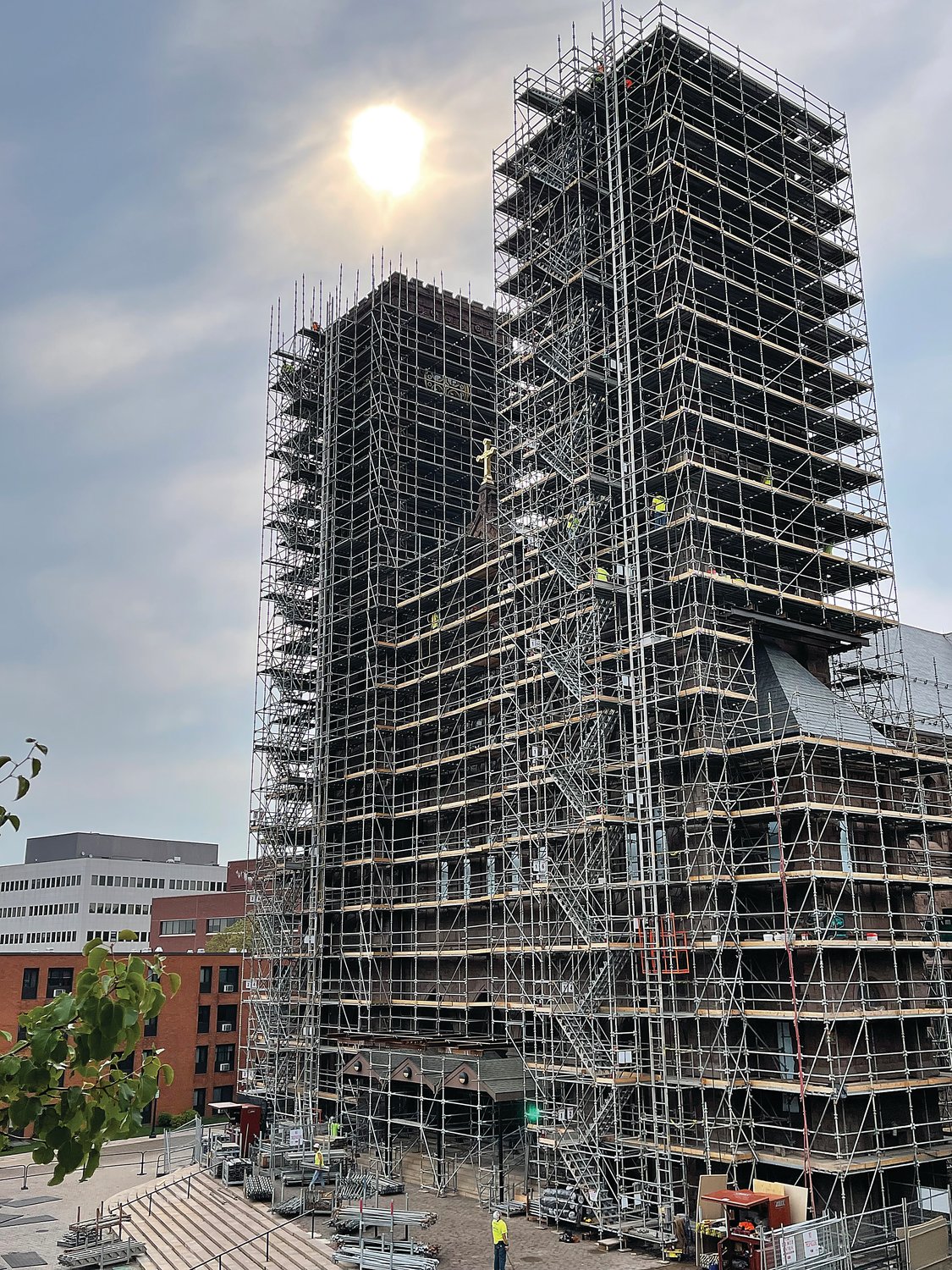 The morning sun shines upon the Cathedral of SS. Peter and Paul on Monday as workers ascend the scaffolding to begin another day of repairs on its sandstone towers.
